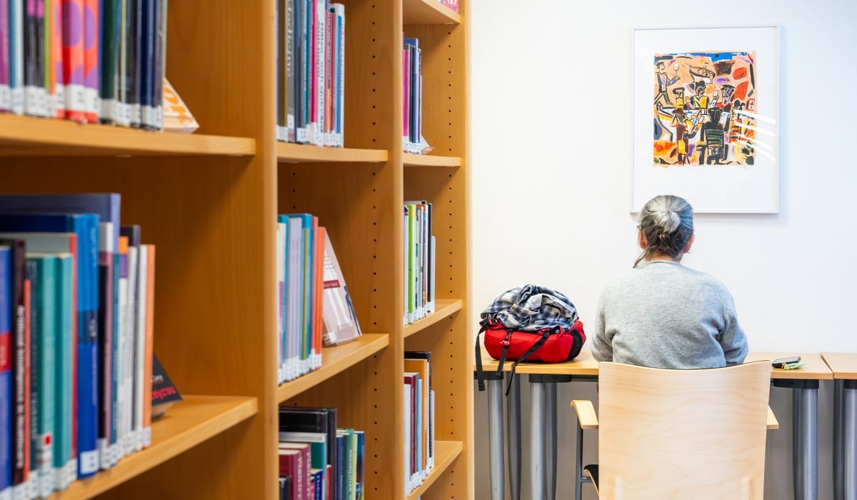 En kvinna sitter vid ett skrivbord i ett bibliotek.